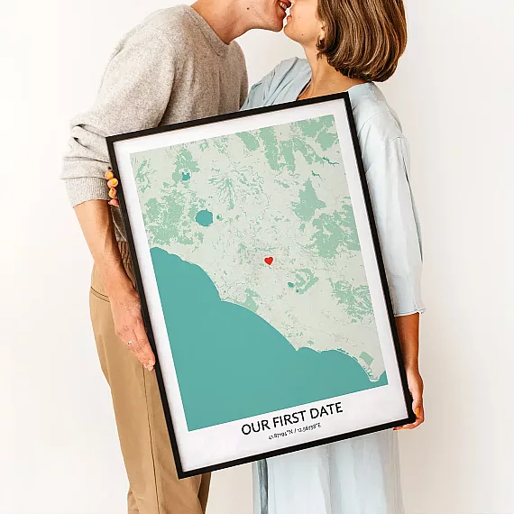 Couple holding Our First Date Map poster with a heart marking the place they first met.
