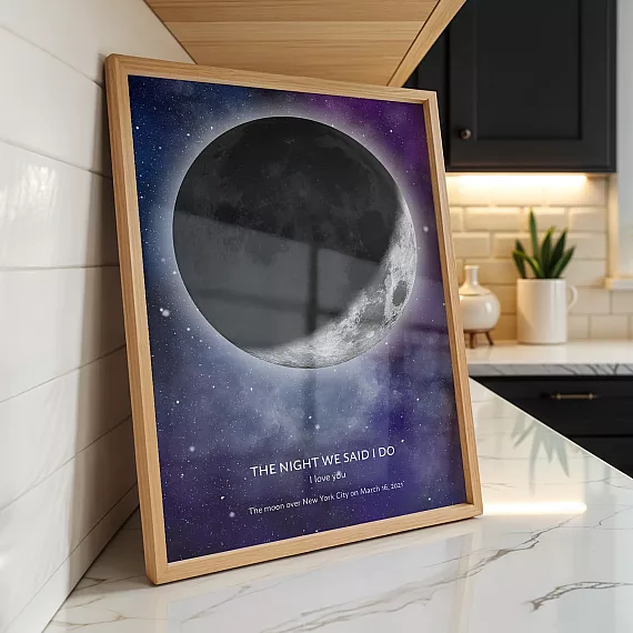 Personalized moon phase poster displayed on a kitchen counter with a glowing moon and custom date text.