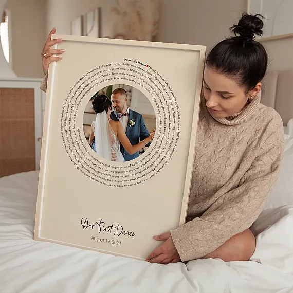 Woman holding First Dance Song Lyrics with Photo poster featuring a wedding photo and circular lyrics design.