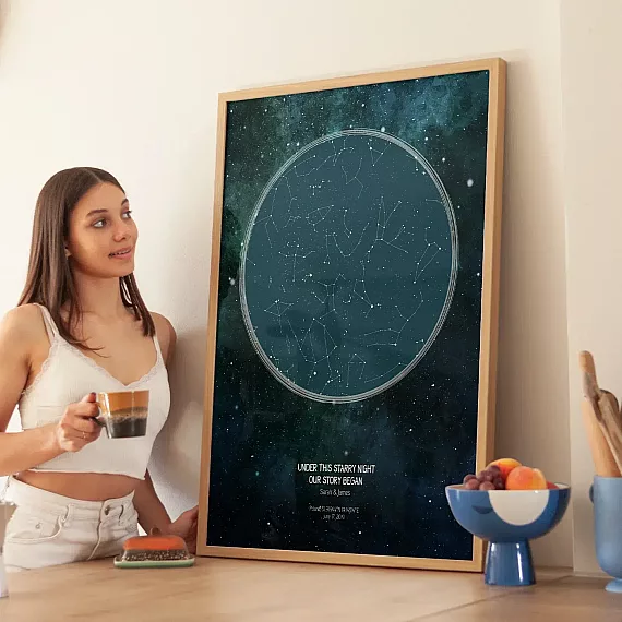 Woman holding a personalized star map poster showing constellations from a special night in a kitchen setting.
