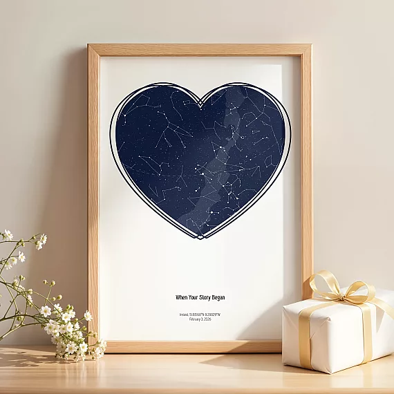 Heart-shaped Birthday Star Map print in wooden frame beside gift box and flowers.