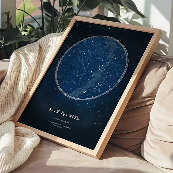 Framed Stars The Night We Met sky map print resting on a sofa beside a knitted blanket in natural sunlight.