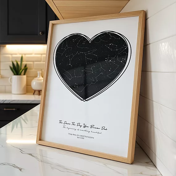 Heart-shaped The Day You Became My Daddy poster displayed on a marble kitchen countertop in a wooden frame.