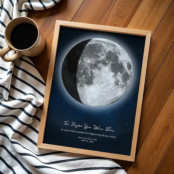 Flat lay birthday moon poster with coffee cup and striped fabric on wooden floor.