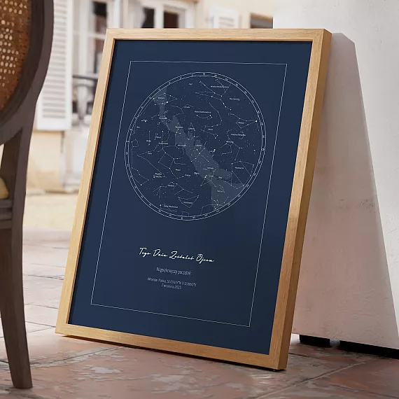 Granatowa mapa nieba w drewnianej ramie oparta o ścianę na tarasie