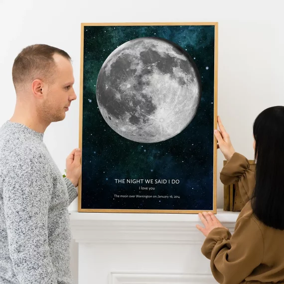 Couple holding The Night We Said I Do moon phase poster with a full moon against a starry background.