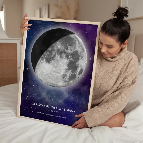 Woman holding a personalized Moon Phase Print while sitting on a bed.