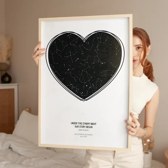 Woman holding a personalized star map poster in a heart shape with constellations from a special date.