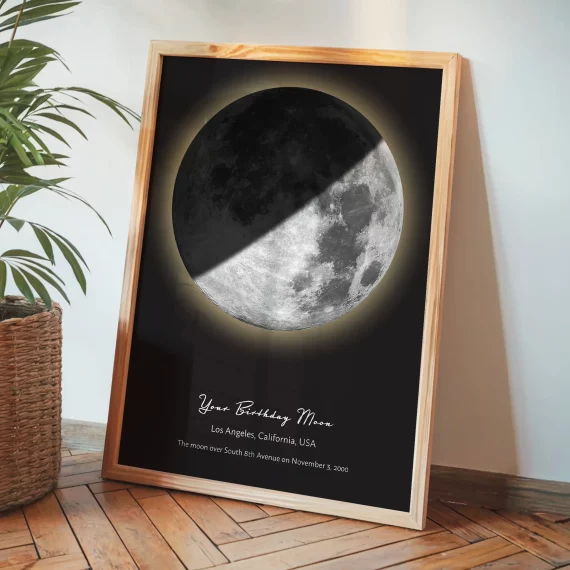 Birthday moon poster with a realistic half moon leaning against a wall beside a plant.