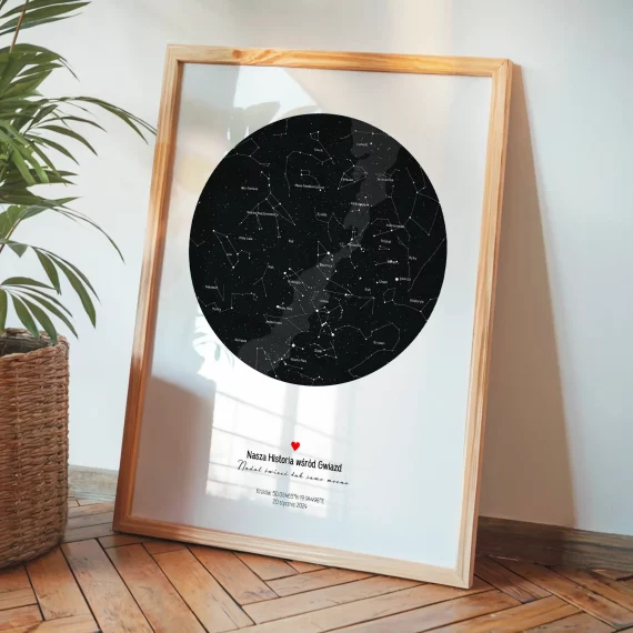 Oprawiona personalizowana mapa nieba z konstelacjami stojąca na drewnianej podłodze obok rośliny