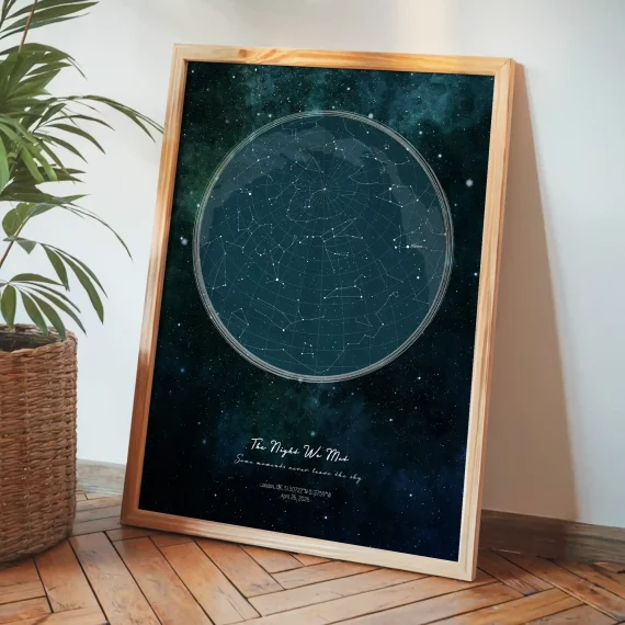Framed personalized star map print leaning beside a plant on wooden flooring.