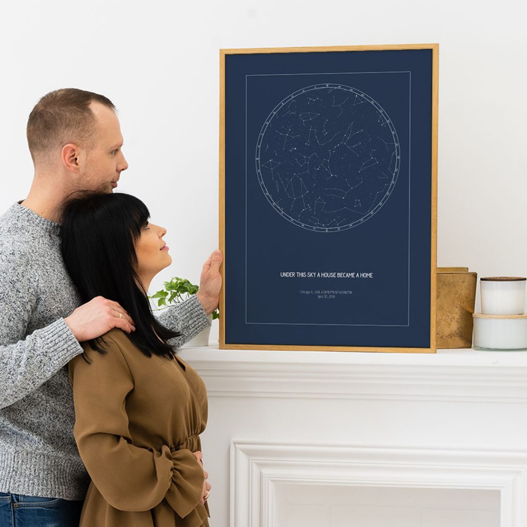 Couple admiring a framed custom star map print displayed on a mantel, ideal as a thoughtful gift for realtors