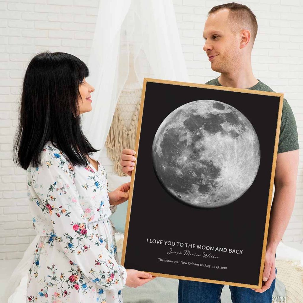 Couple holding a personalized moon phase print with the message “I Love You to the Moon and Back.”