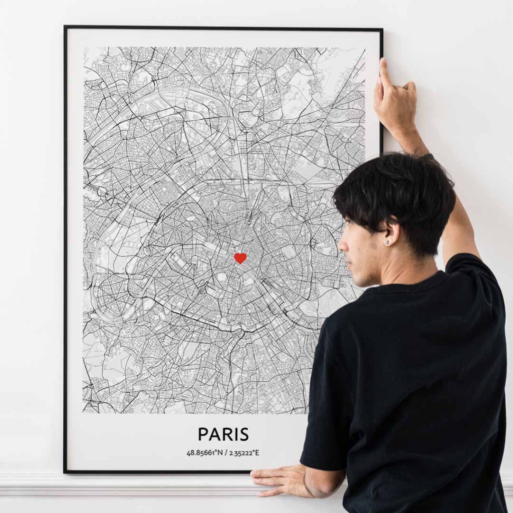 Person hanging a custom Paris map print on the wall, turning travel memories into minimalist wall art.