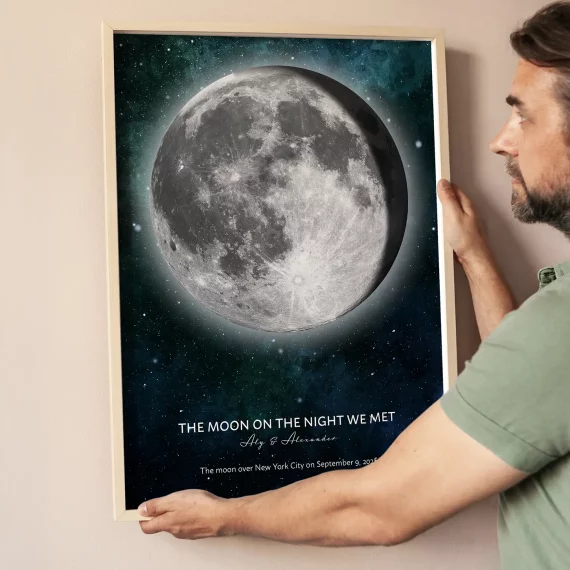 Man hanging a personalized Moon on the Night We Met print featuring the exact moon phase.