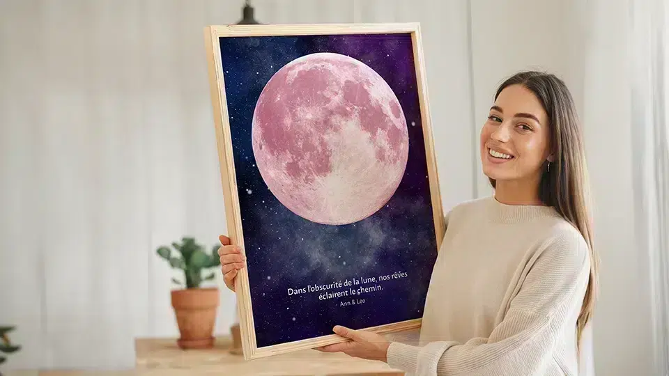 Comprendre les phases de la Lune : femme souriante présente poster lune rose "Dans l'obscurité de la lune" en cadre bois