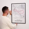 Man hanging a personalised custom route map poster with a red running route, city map, distance, time, date, and elevation details.